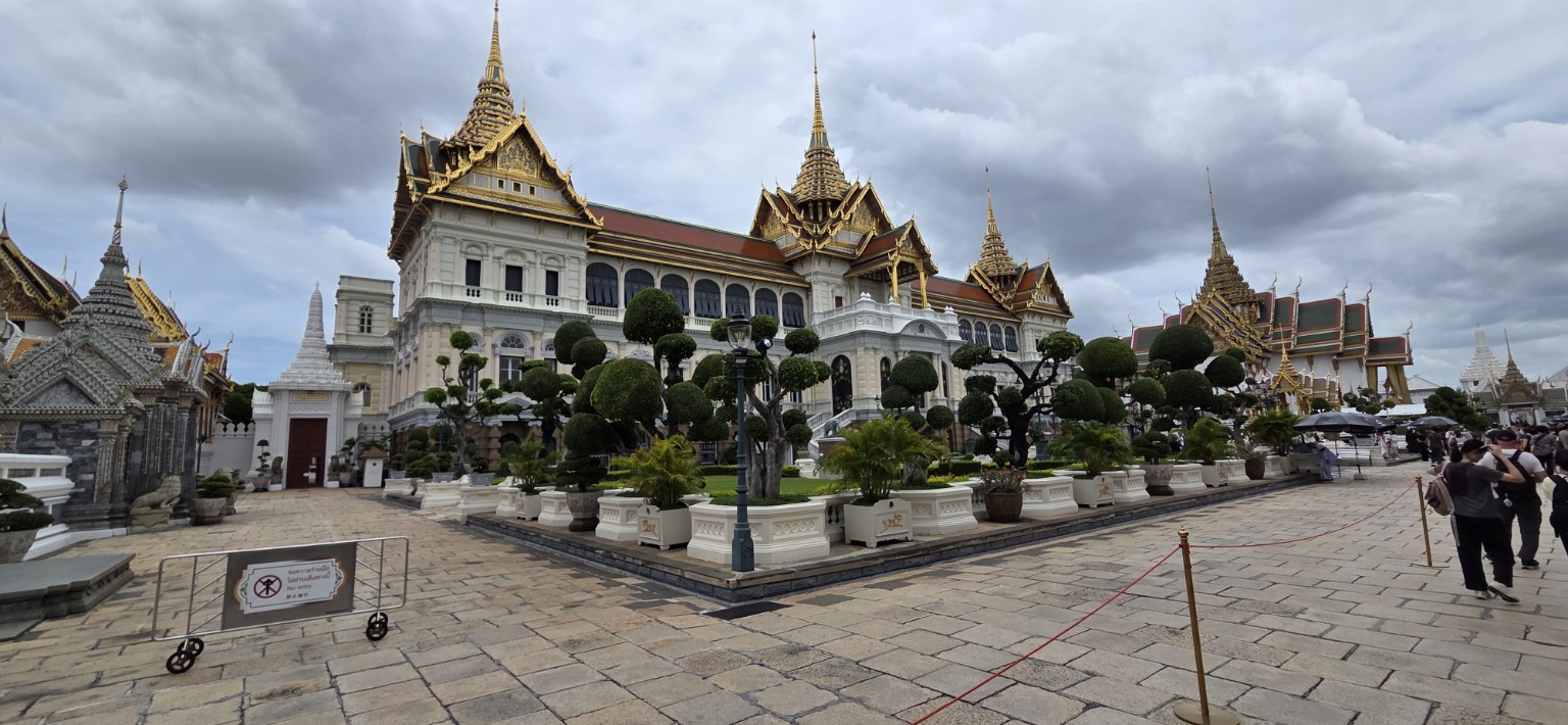 Panoramic view of Chakri Maha Prasat Hall and its gardens beneath storm clouds