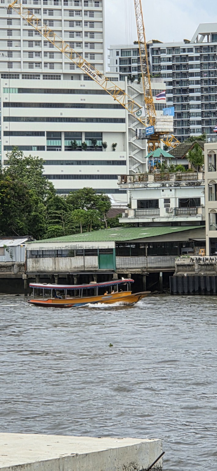 Orange long-tail passenger boat crossing the river