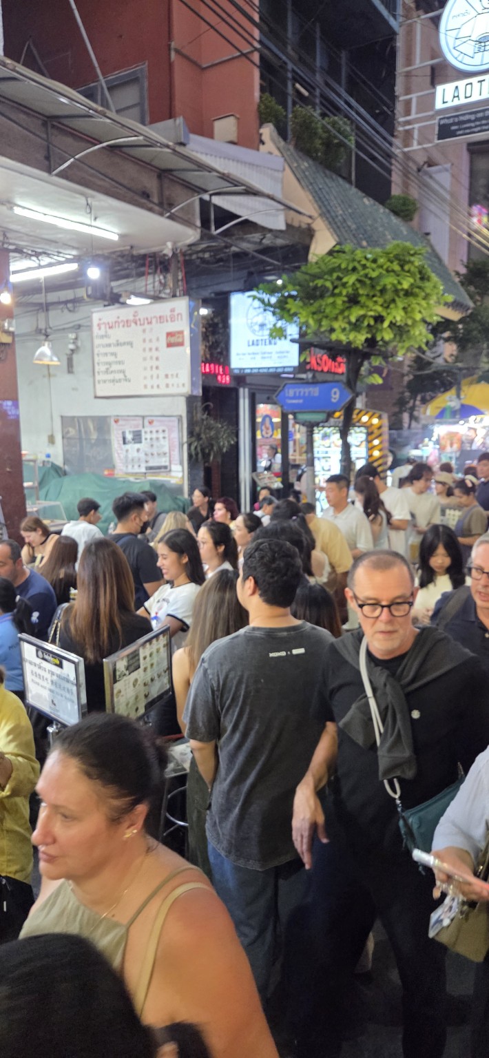 A packed sidewalk beside food stalls in Yaowarat